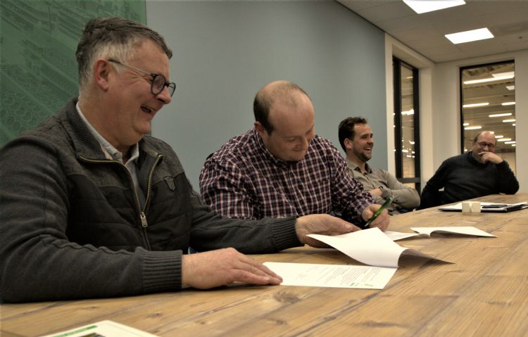 Raymond Florack tekent onder toeziend oog van Hans Linders en andere DQG leden de samenwerking.