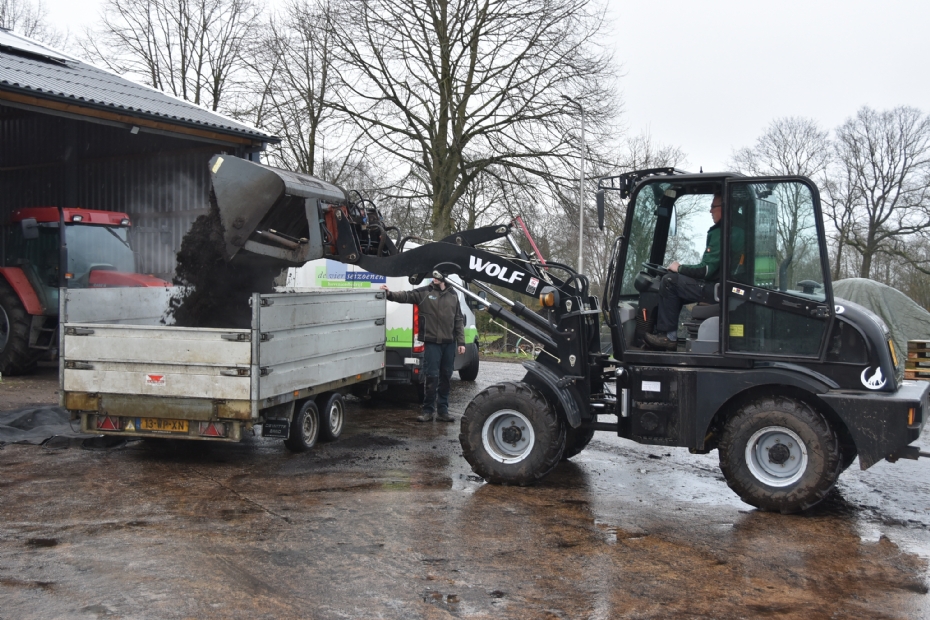 Een tweeassige kipwagen met een grote laadbak, beladen met compost Een tweeassige kipwagen met een grote laadbak, beladen met compost