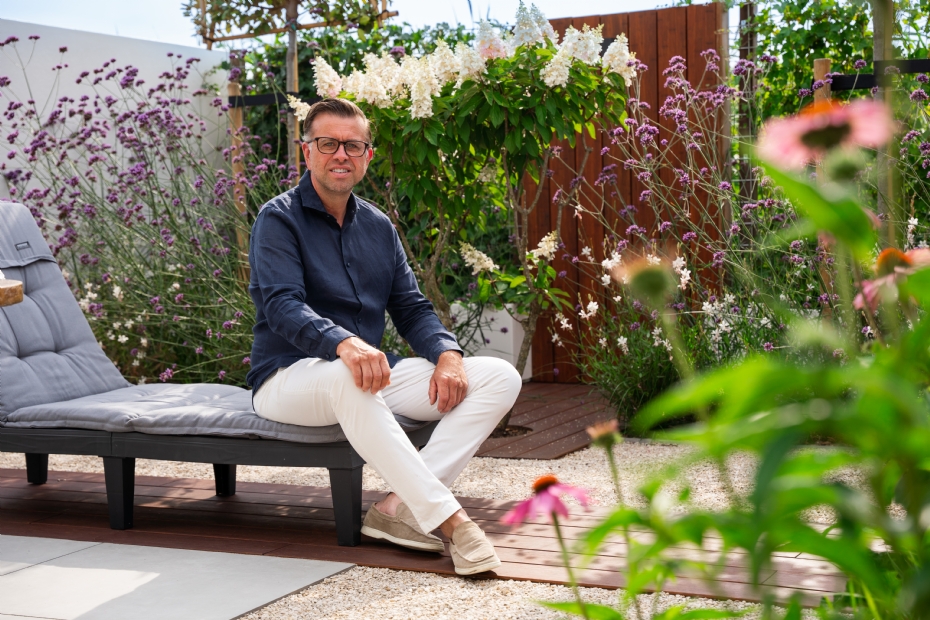 Leon de Winter zit in een tuin die volop ruimte biedt om te ontspannen.